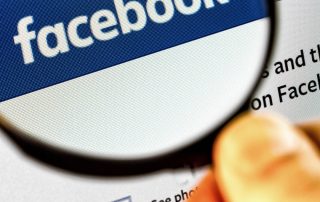 Facebook-Logo unter einer Lupe, symbolisiert Datenschutz- und Marketingaspekte von Facebook Pixel im Gesundheitswesen.